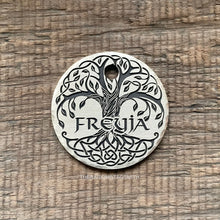 Load image into Gallery viewer, A silver round tag with a tree of life design engraved on it. The tree has a thick trunk and branches with leaves. The roots are intertwined and form a Celtic knot design. The name &#39;FREYJA&#39; is engraved in the center of the tag.