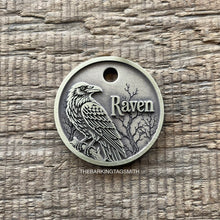 Load image into Gallery viewer, Personalized raven pet ID tag engraved with a detailed raven perched among haunted bare trees and a custom pet name.