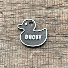 Load image into Gallery viewer, Metal rubber duck-shaped tag with 'DUCKY' text on a wooden surface