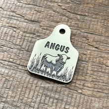 Load image into Gallery viewer, Dog ID tag shaped like a livestock ear tag with cow design deep engraved on metal tag, personalised engraved pet tag with the name Angus.