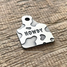 Load image into Gallery viewer, Dog ID tag shaped like a cattle ear tag with cow print pattern and engraved name Garrett, personalised deep engraved metal pet tag.