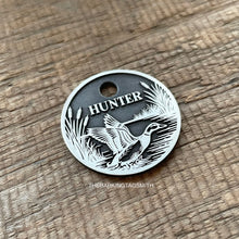 Load image into Gallery viewer, Dog ID tag with duck hunting scene deep engraved on round metal tag, personalised pet tag featuring flying duck, reeds and water design