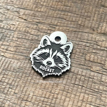 Load image into Gallery viewer, Dog ID tag shaped like a raccoon face with detailed deep engraved raccoon design and the name Rocket, personalised engraved metal pet tag.