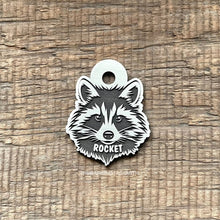 Load image into Gallery viewer, Dog ID tag shaped like a raccoon face with detailed deep engraved raccoon design and the name Rocket, personalised engraved metal pet tag.