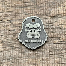 Load image into Gallery viewer, Dog ID tag shaped like a Sasquatch Bigfoot face with deep engraved details and the name Sasquatch, personalised engraved metal pet tag for cryptid fans.