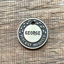 Load image into Gallery viewer, Personalised wizard map dog ID tag with engraved magical footprints and fantasy-inspired lettering in brushed silver metal on rustic wood background