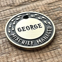 Load image into Gallery viewer, Personalised wizard map dog ID tag with engraved magical footprints and fantasy-inspired lettering in brushed silver metal on rustic wood background